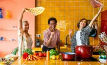 Trois amis souriants s’amusent ensemble dans une cuisine colorée - Three smiling friends have fun together in a colorful kitchen