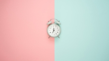 horloge au centre d'un fond moitié rose et moitié turquoise