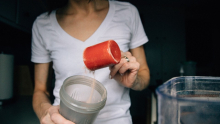Femme qui met un tasse de protéines dans un malaxeur