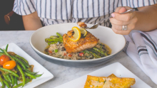 Femme qui mange du saumon sur lit d'asperges et riz aux légumes