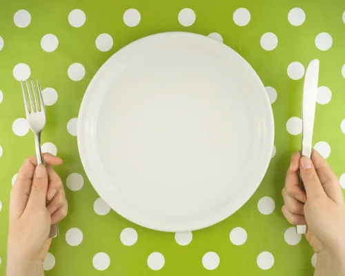 Assiette et mains sur une nappe verte à pois