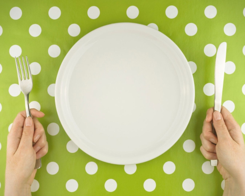 Assiette et mains sur une nappe verte à pois