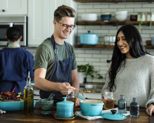 homme et femme souriants en cuisinant