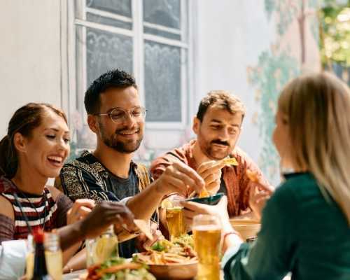 Un groupe d'amis partageant un repas dans un restaurant à Nepean, Ottawa, échangeant nourriture et boissons dans une ambiance décontractée et conviviale.