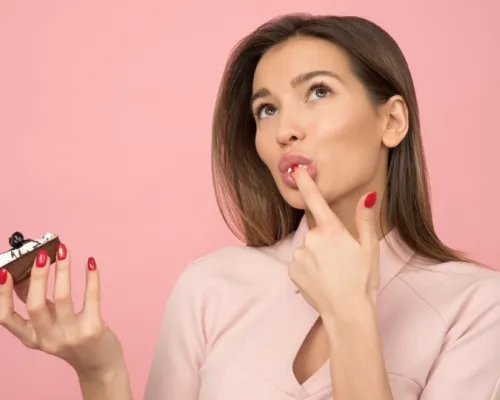 Femme qui mange un gateau devant un écran rose