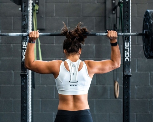 femme de dos musclée qui lève un haltère