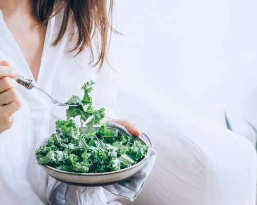 Fille habillée en blanc qui mange une salade de kale