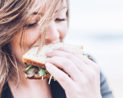 Fille qui mange un sandwich avec du vent dans les cheveux