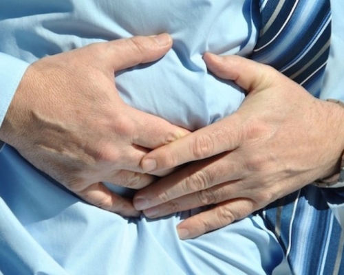 homme avec une chemise bleu qui a des douleurs abdominales