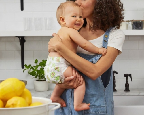 femme tenant son bébé dans les bras dans une cuisine