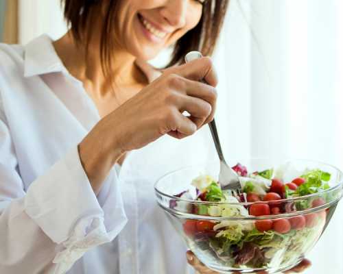 a person holding a bowl of salad in front of a window