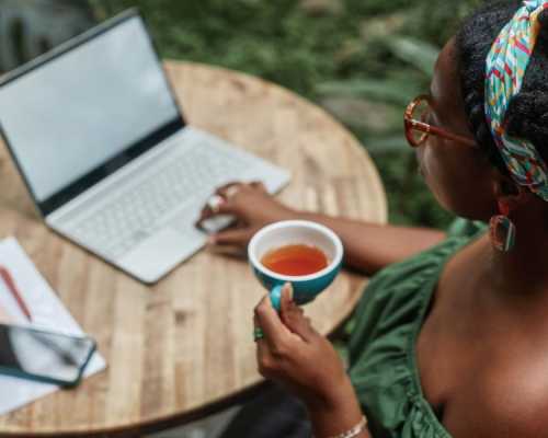 Femme buvant une tasse de thé devant son ordinateur