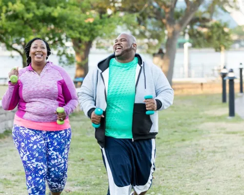 A smiling plus size couple jogs outdoors - Un couple en surpoids souriant fait du jogging en extérieur