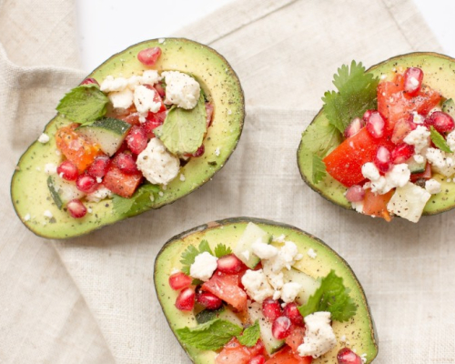 Trois moitiés d'avocat farcies avec feta, tomates, menthe et grenade