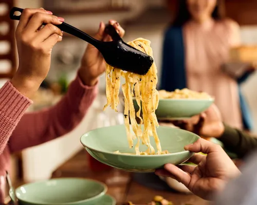 Gros plan d'une personne servant des pâtes fraîchement cuites - Close-up of a person serving freshly cooked pasta