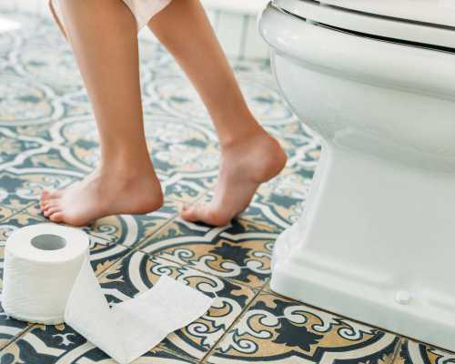 Pieds nus sur un sol carrelé à motifs à côté d'une toilette - Bare feet on patterned tile floor next to a toilet