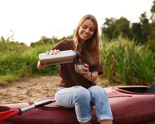 femme qui se verse une boisson assise sur un kayak à Cap-Rouge ÉquipeNutrition TeamNutrition