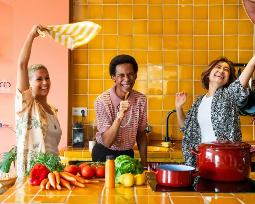 Trois amis souriants s’amusent ensemble dans une cuisine colorée - Three smiling friends have fun together in a colorful kitchen