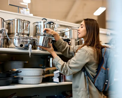 Femme choisissant une casserole en acier inoxydable dans un magasin de cuisine - Woman choosing a stainless steel pot in a kitchenware store