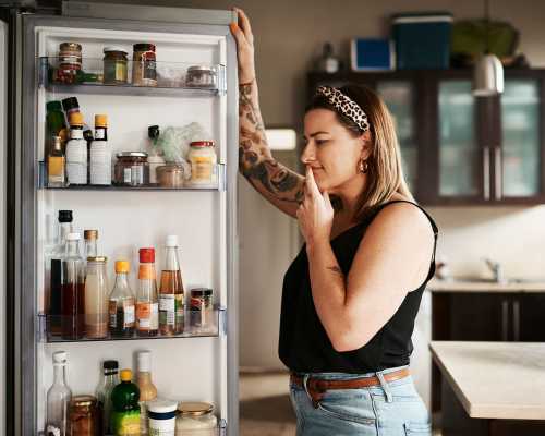 Femme regardant dans le réfrigérateur - Woman looking at fridge content