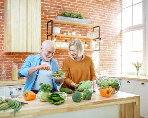 Deux jeunes femmes discutent lors d'une consultation en nutrition, assises à une table blanche dans une cuisine lumineuse. L'une d'elles explique avec des gestes, tandis que l'autre écoute attentivement.