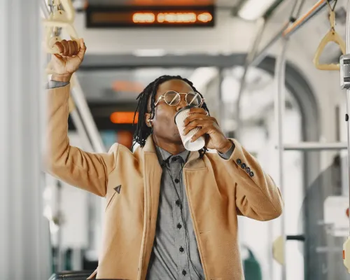 Homme tenant une poignée et buvant un café dans un autobus - Man holding a handle and drinking coffee on a bus