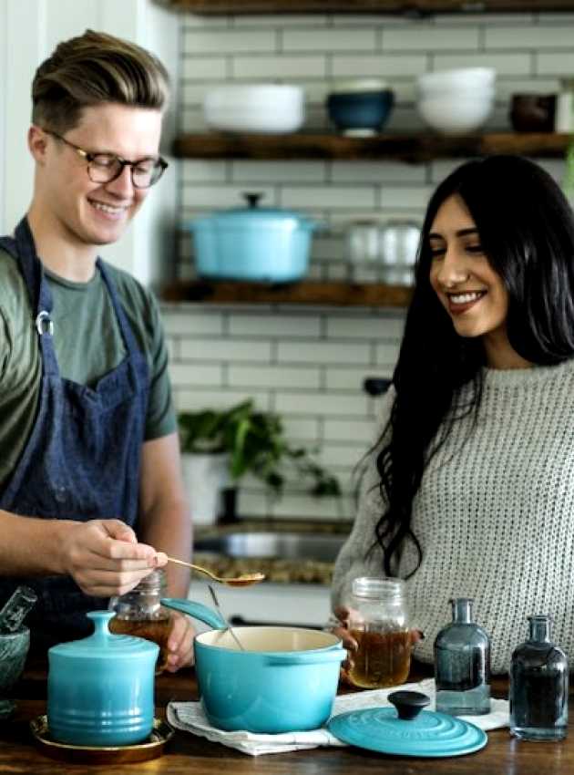 homme et femme souriants en cuisinant