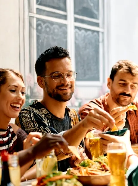 Un groupe d'amis partageant un repas dans un restaurant à Nepean, Ottawa, échangeant nourriture et boissons dans une ambiance décontractée et conviviale.