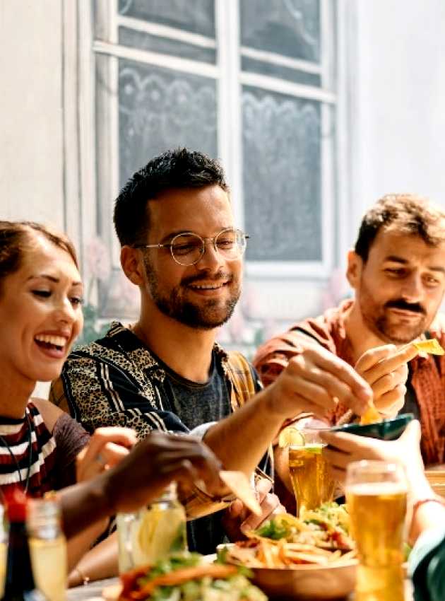 Un groupe d'amis partageant un repas dans un restaurant à Nepean, Ottawa, échangeant nourriture et boissons dans une ambiance décontractée et conviviale.