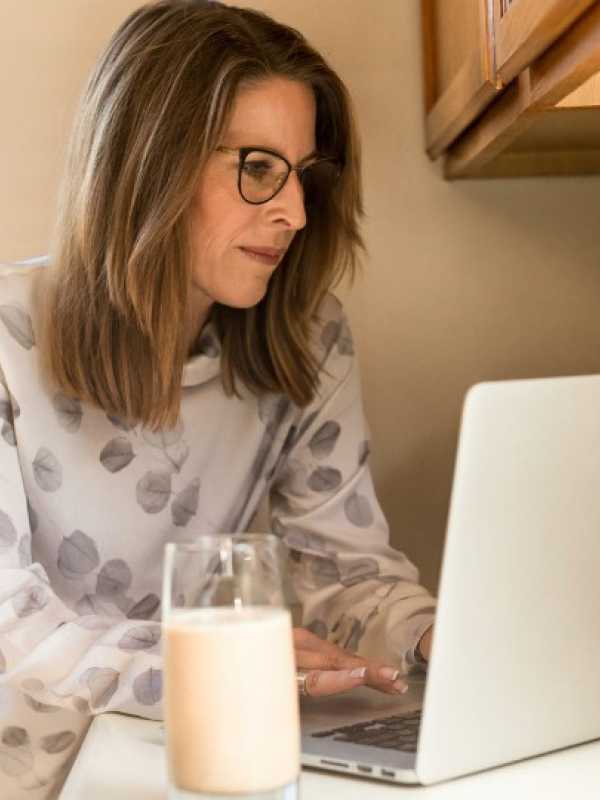 femme ménopausé devant un ordinateur avec un verre de lait