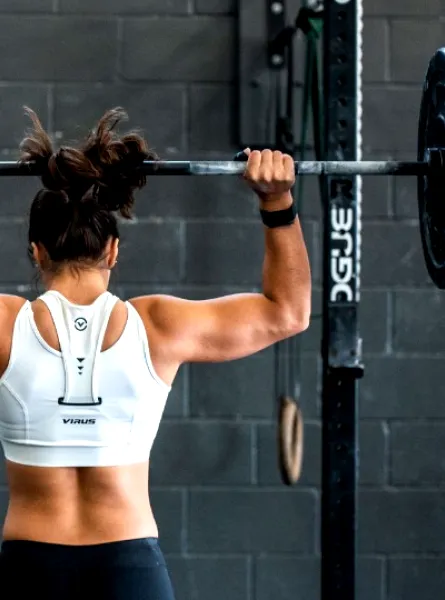 femme de dos musclée qui lève un haltère