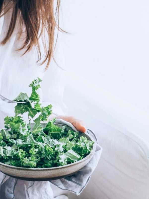 Fille habillée en blanc qui mange une salade de kale