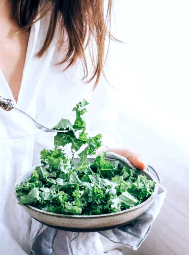 Fille habillée en blanc qui mange une salade de kale