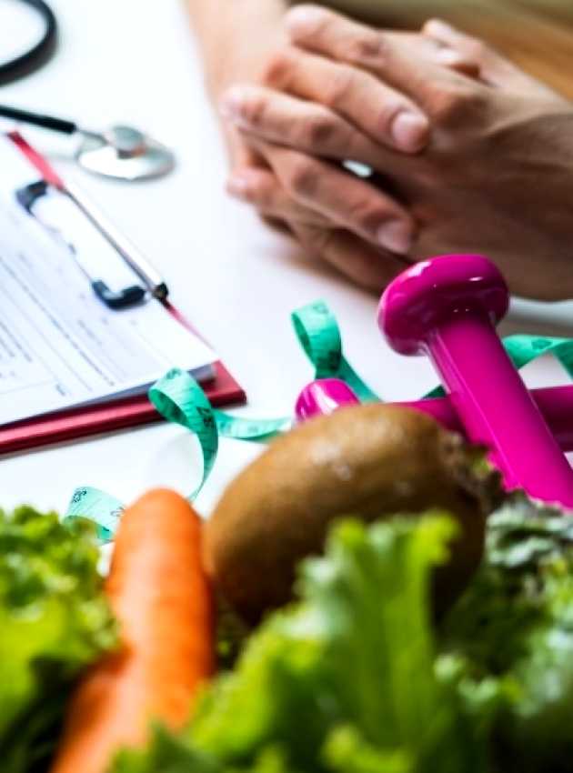 Nutritionniste-diététiste à Toronto qui fait une consultation en nutrition avec un client en tenant une pomme et en prenant des notes.