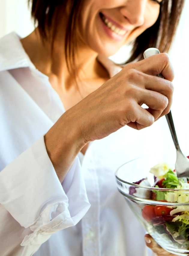 a person holding a bowl of salad in front of a window