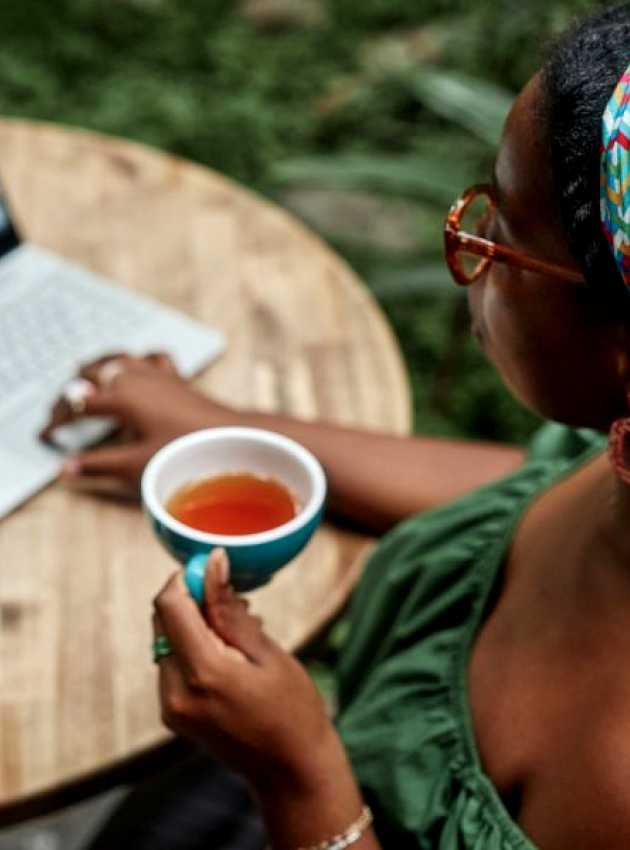 Femme buvant une tasse de thé devant son ordinateur