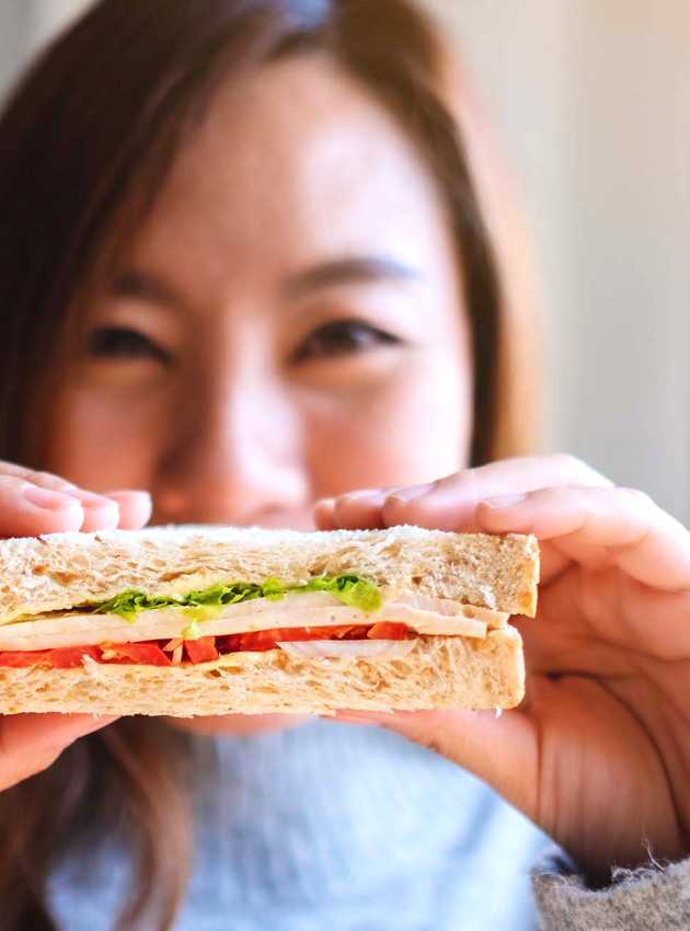 A smiling woman holding a sandwich - Une femme souriante tenant un sandwich