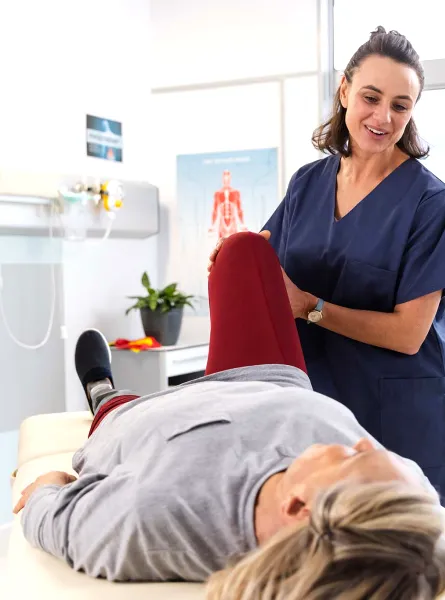 Physiotherapist assisting a patient with a leg stretch -  Physiothérapeute aidant un patient à étirer la jambe