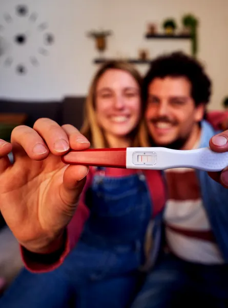 Couple heureux sourit en tenant un test de grossesse positif - Happy couple smiling and holding a positive pregnancy test