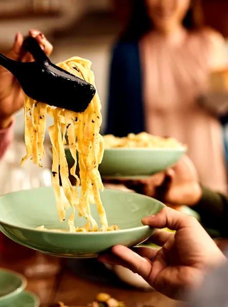 Gros plan d'une personne servant des pâtes fraîchement cuites - Close-up of a person serving freshly cooked pasta