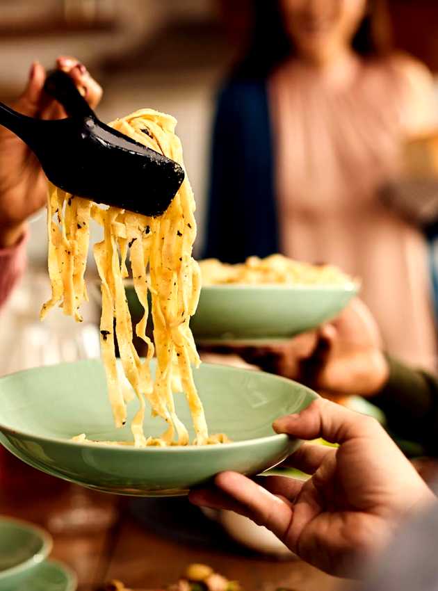 Gros plan d'une personne servant des pâtes fraîchement cuites - Close-up of a person serving freshly cooked pasta