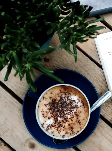 Un agenda, un café et une plante sur une table en bois
