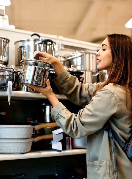 Femme choisissant une casserole en acier inoxydable dans un magasin de cuisine - Woman choosing a stainless steel pot in a kitchenware store