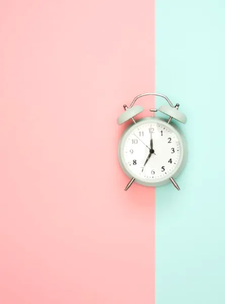 horloge au centre d'un fond moitié rose et moitié turquoise