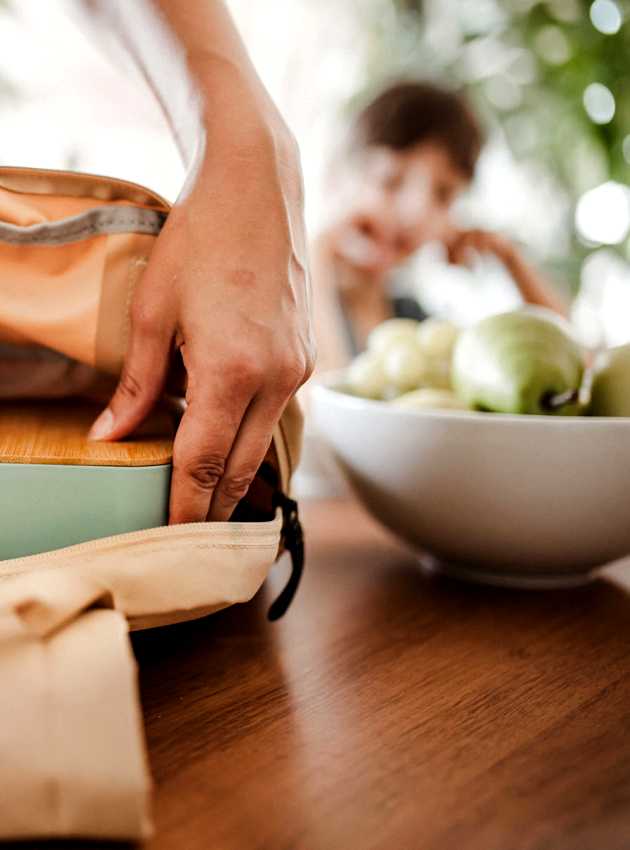 Personne en train de préparer un sac avec une boîte à lunch et une bouteille - Person packing a bag with a lunchbox and a bottle