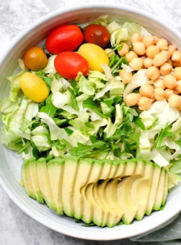 un bol de salade avec avocat, tomates et pois chiches