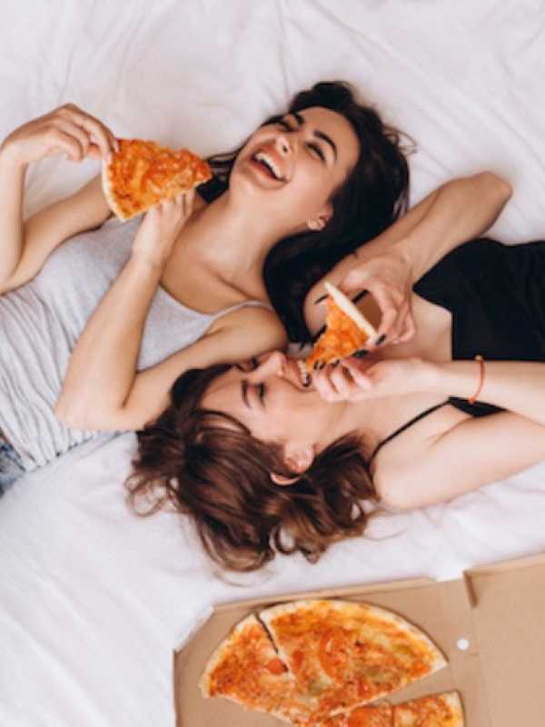 femmes qui mangent de la pizza sur le lit