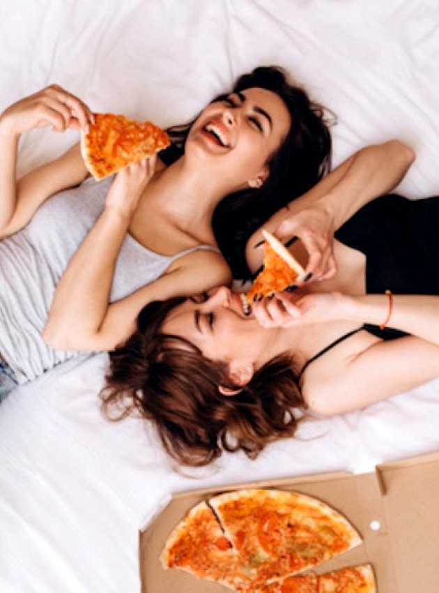 femmes qui mangent de la pizza sur le lit