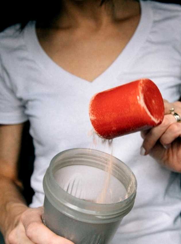 Femme qui met un tasse de protéines dans un malaxeur