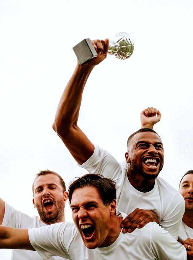 Group of excited men in white jerseys celebrating victory as one holds up a trophy - Groupe d'hommes enthousiastes en maillots blancs célébrant leur victoire, l'un d'eux brandissant un trophée